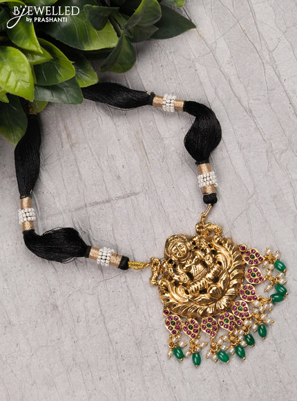 Black thread necklace with kemp stone lakshmi pendant and green beads hanging without earrings