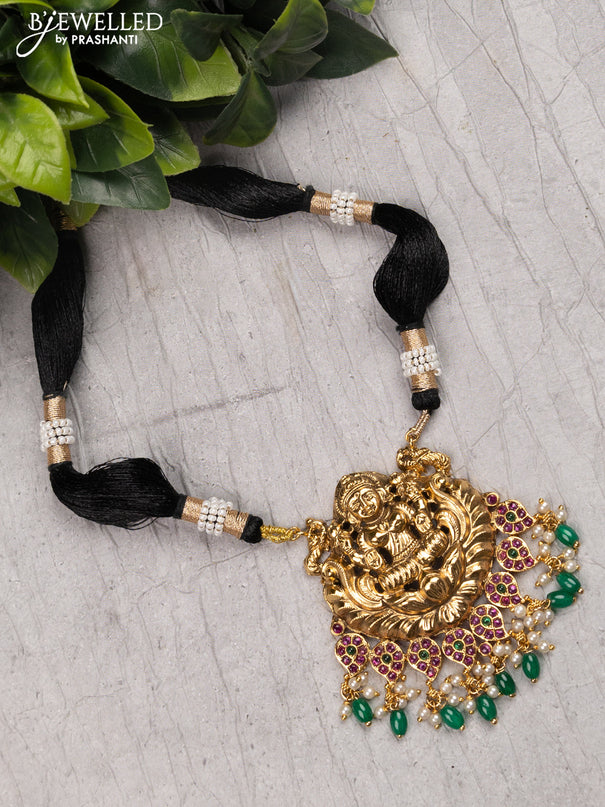 Black thread necklace with kemp stone lakshmi pendant and green beads hanging without earrings