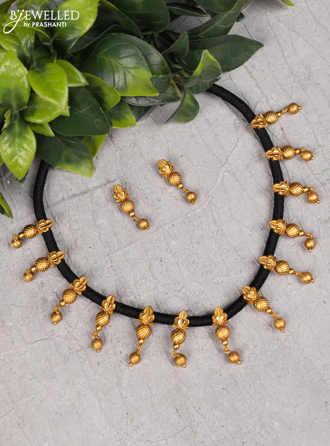 Black thread necklace with golden beads hanging