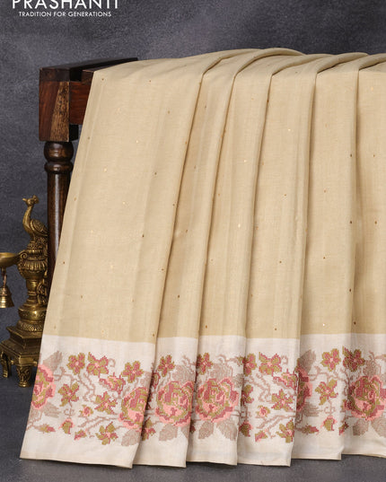 Tussar silk saree beige and cream with allover zari buttas and floral design cross stitched embroidery border