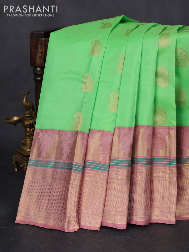 Pure kanchipuram silk saree green shade and pastel peach with paisley zari woven buttas and long temple design zari woven korvai border