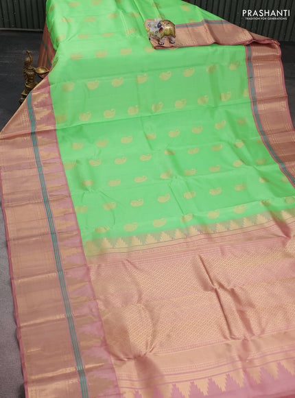 Pure kanchipuram silk saree green shade and pastel peach with paisley zari woven buttas and long temple design zari woven korvai border