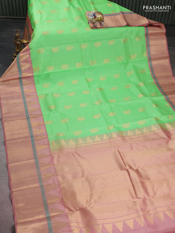 Pure kanchipuram silk saree green shade and pastel peach with paisley zari woven buttas and long temple design zari woven korvai border