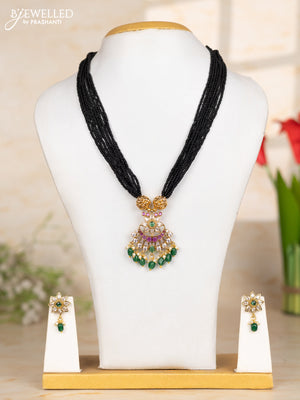 Beaded black necklace with floral pendant in kemp and green beads hanging
