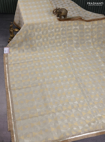 Banarasi tissue saree beige and dark green with allover zari woven geometric wevaes and lace work border