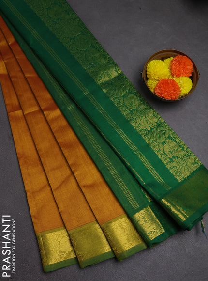 Silk cotton saree dark mustard and green with plain body and peacock zari woven border