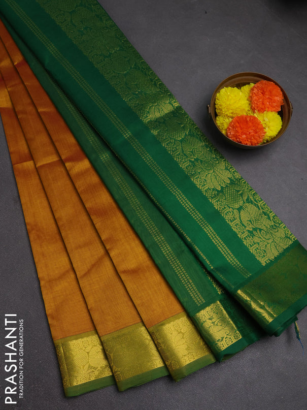 Silk cotton saree dark mustard and green with plain body and peacock zari woven border